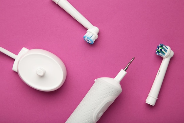 Modern electric toothbrush with charger on pink background