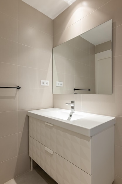 Modern empty bathroom with beige tiles furniture and rectangular mirror