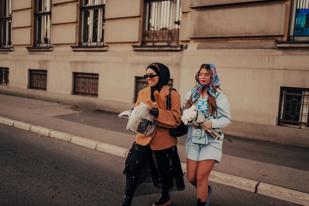 A modern European woman and a Muslim woman with a hijab walking the streets of the city dressed in clothes from the 19th century while carrying newspapers, flowers, and bread in their hands.