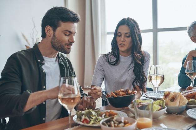 Modern family communicating and smiling while having dinner together