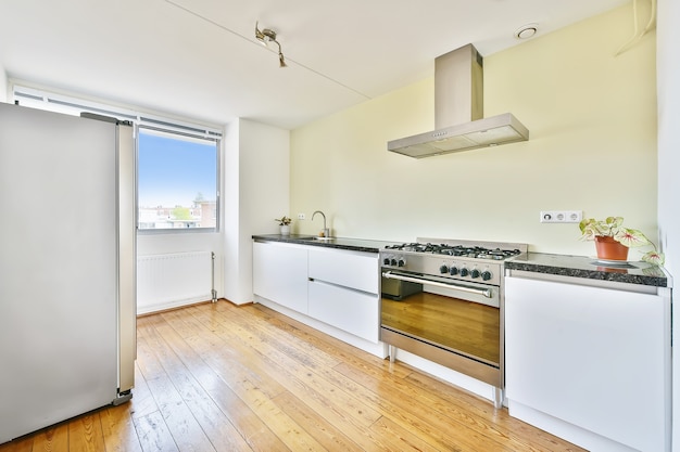 Photo modern galley kitchen with wooden cabinets and minimalist design in studio attic apartment with white walls