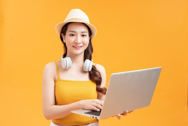 Modern girl buys tickets online, portrait on a background of an yellow wall