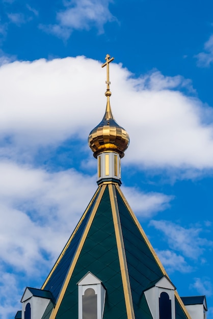 Modern Golden dome with a cross on the green roof of the Orthodox Christian Church