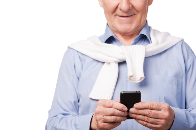 Modern grandfather. Happy senior man holding mobile phone while standing against white background