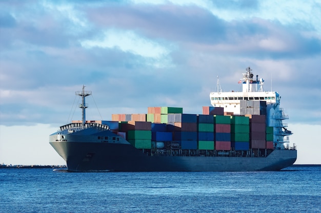 Modern grey container ship moving in still water