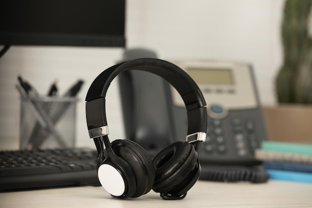 Modern headphones desktop telephone and computer on table indoors