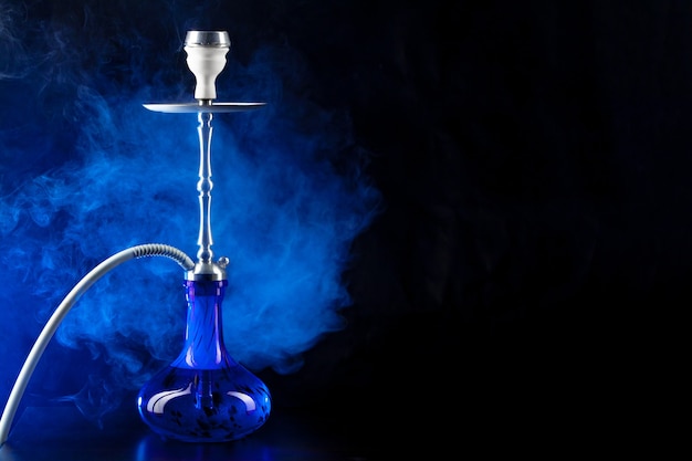 Modern hookah with smoke in dark club light close up