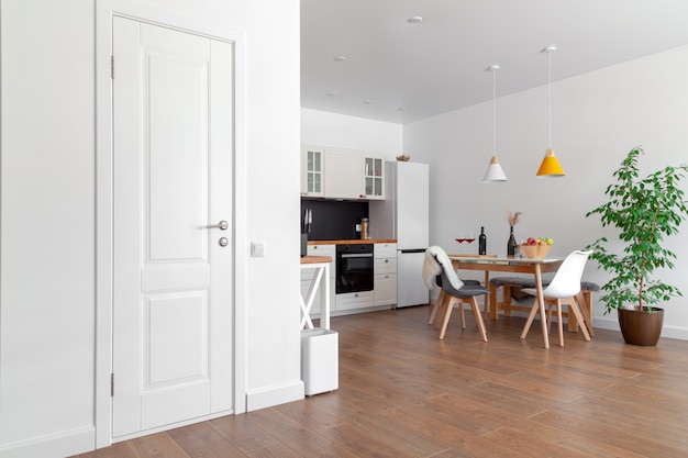 Modern interior of kitchen, white wall, wooden chairs, green flower in pot. Concept scandinavian design