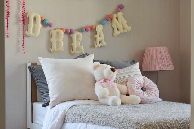 Modern kids room with doll and pillows on bed