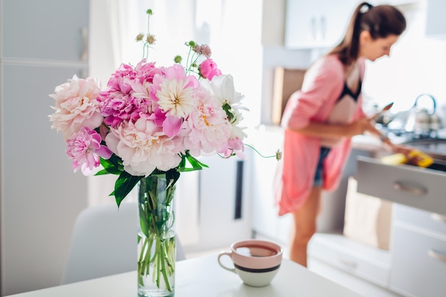 Modern kitchen decorated with pink peonies housewife cooking dinner interior design