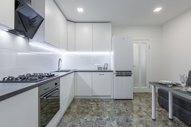 modern kitchen in light white tones with black marble tiles on the floor placed in a small apartment