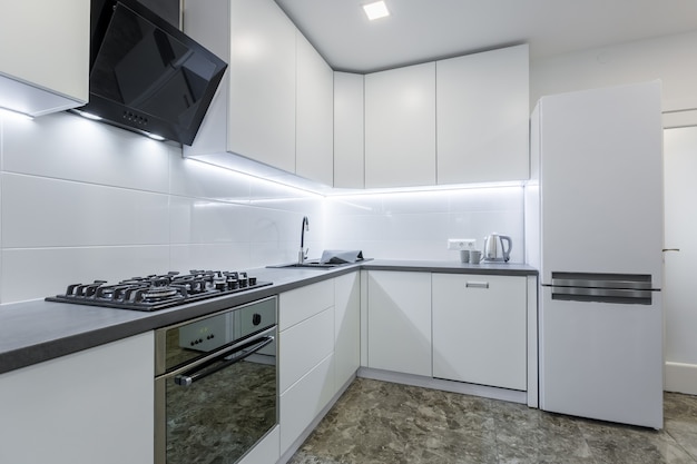 modern kitchen in light white tones with black marble tiles on the floor placed in a small apartment