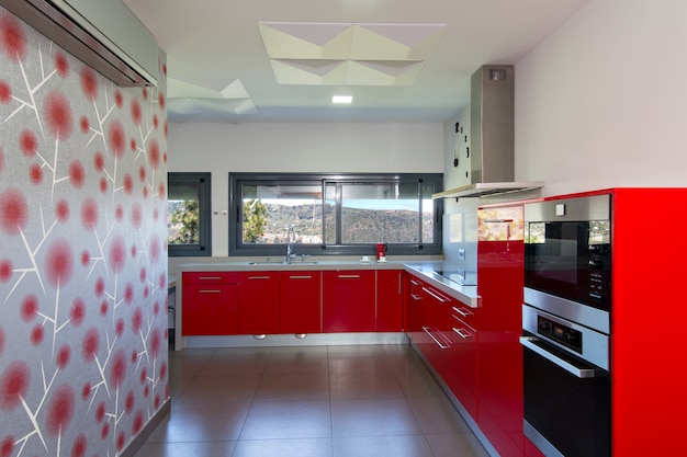 Modern kitchen in red, with exterior view. Interior design of house.