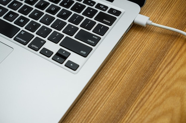 A modern laptop computer stands on a wooden table