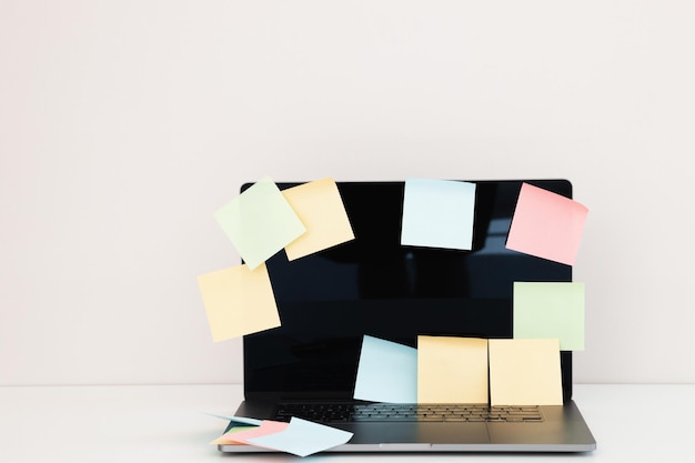 Photo modern laptop and different sticky notes on white wall