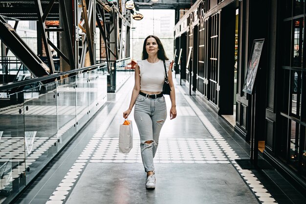 Modern latina young woman walking in large modern mall young pretty brunette female consumer