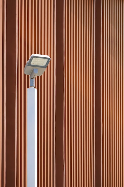 Modern LED solar power street light post against wooden trellis wall outside of vintage building