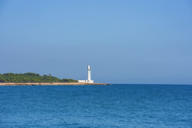 Modern lighthouse in the Mediterranean Sea. No clouds, blue sky, sunny day.