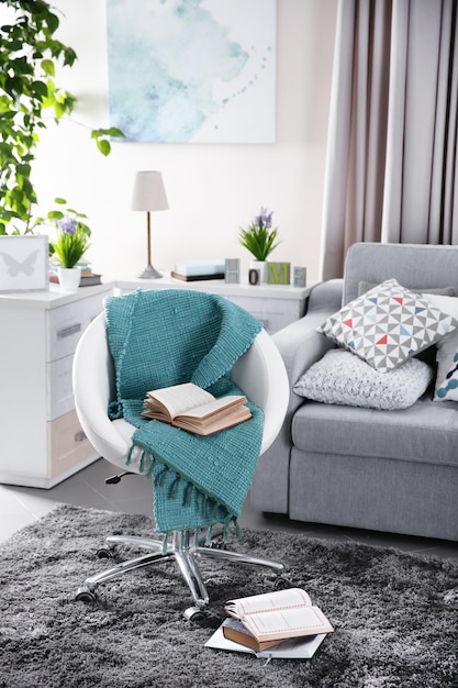 Modern living room interior in grey tones with bright blue plaid and book on chair