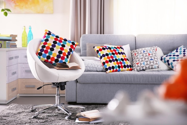 Modern living room interior in grey tones with colourful pillow on chair