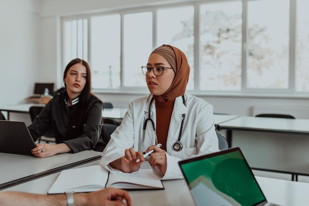 In a modern meeting room a muslim female doctor wearing a hijab engages in a discussion with her