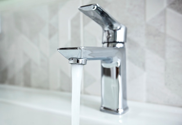 The modern metal faucet in the bathroom