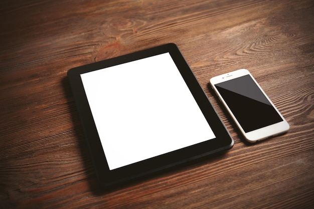 Modern mobile phone and tablet on wooden background