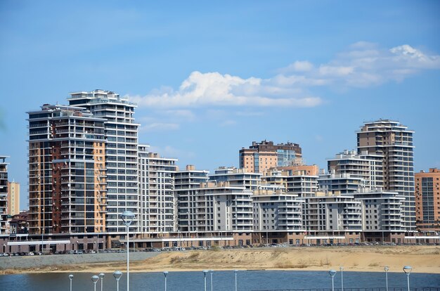 Modern multi-storey building in the city on the shore on blue sky surface