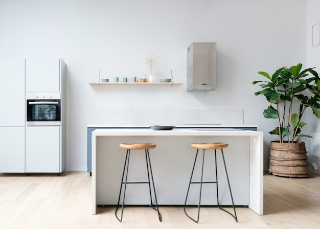 Modern new light interior of kitchen with white furniture and dining table.