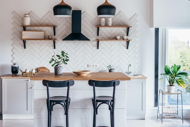 Modern new light interior of kitchen with white furniture and dining table