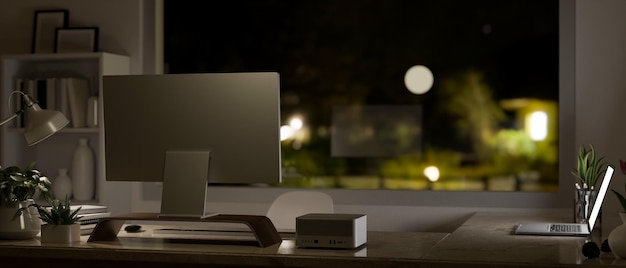 Modern office desk in the darkness room at night with pc computer laptop on the table back view