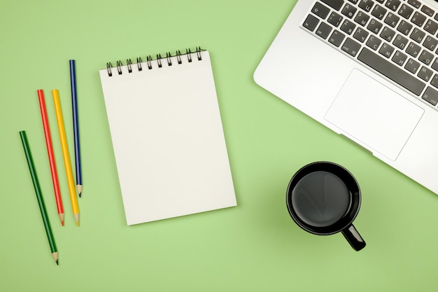 Modern office desk table with laptop blank notebook page for input the text in the middle and other supplies Top view flat lay