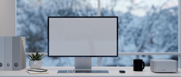 Modern office desk with computer mockup supplies and decor over the window with snow view