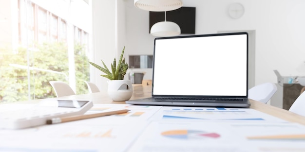 Modern office desk with open laptop computer white screen mockup financial and marketing report calculator and supplies