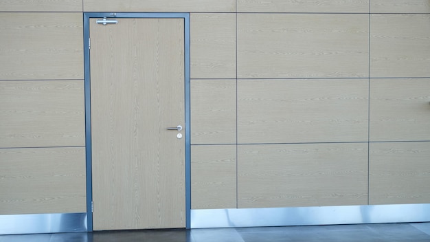 Modern office lobby with wooden walls brown door white wall and vertical poster