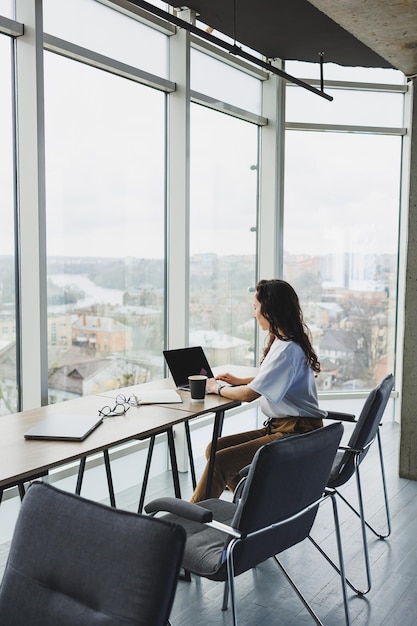 Modern office woman worker in casual clothes works on a laptop Female manager at workplace working on new project using laptop modern workspace