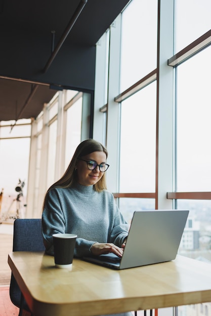 Modern office woman worker in casual clothes works on a laptop Female manager at workplace working on new project using laptop modern workspace