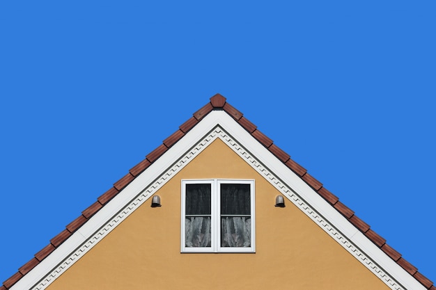 Modern orange house gable roof design wall with clear blue sky background.