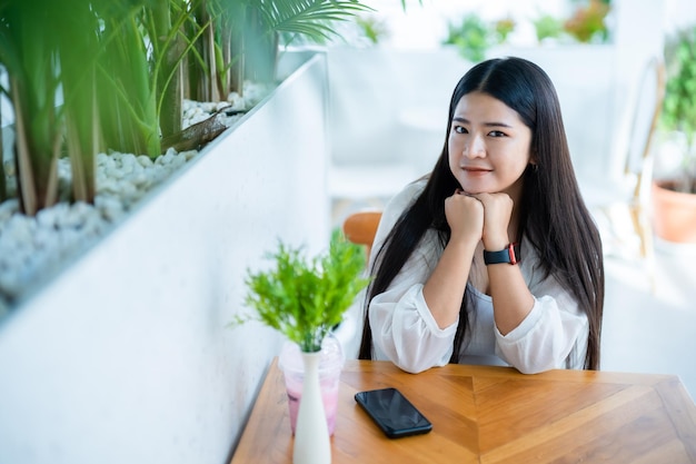 Modern portrait of beautiful happy asian woman traveler wearing smartwatch wearing beautiful white dress and wear jeans lifestyle enjoying in sitting coffee shop restaurant background