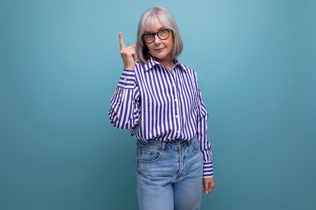 Modern s middle aged woman with gray hair in a stylish look with a brilliant idea on a bright studio