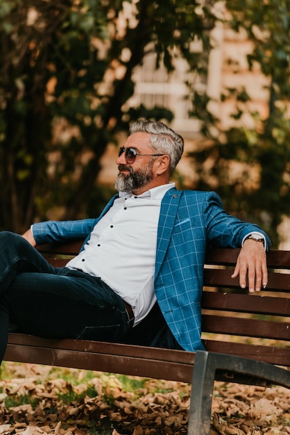 Modern senior businessman resting on a bench in the city on a break from work