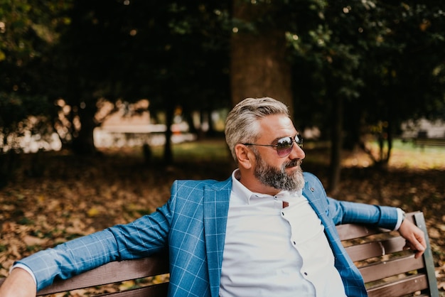 Modern senior businessman resting on a bench in the city on a break from work