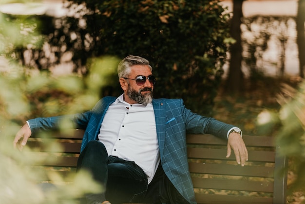 Modern senior businessman resting on a bench in the city on a break from work.