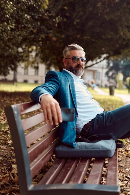 Modern senior businessman resting on a bench in the city on a break from work.