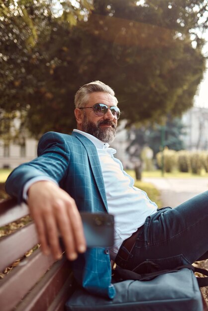 Modern senior businessman resting on a bench in the city on a break from work.