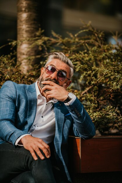 Modern senior businessman resting on a bench in the city on a break from work.