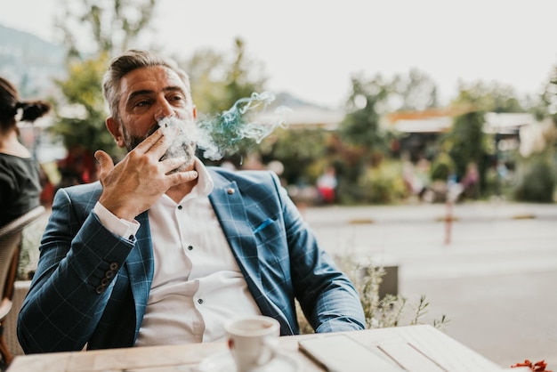 Modern senior businessman smokes a cigarette while resting in a cafe after a hard day39s work