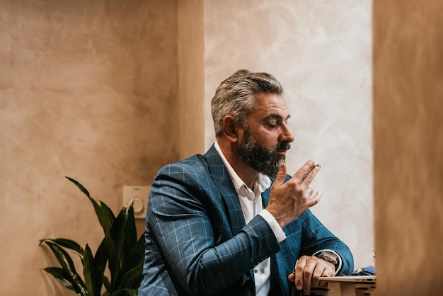 Modern senior businessman smokes a cigarette while resting in a cafe after a hard day39s work