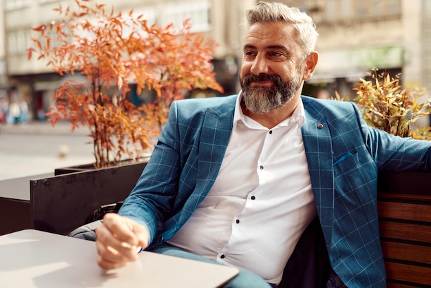 Modern senior businessman smoking a cigarette while resting in a cafe after a hard day's work.