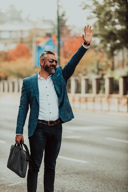 Modern senior businessman stopping a taxi in the city